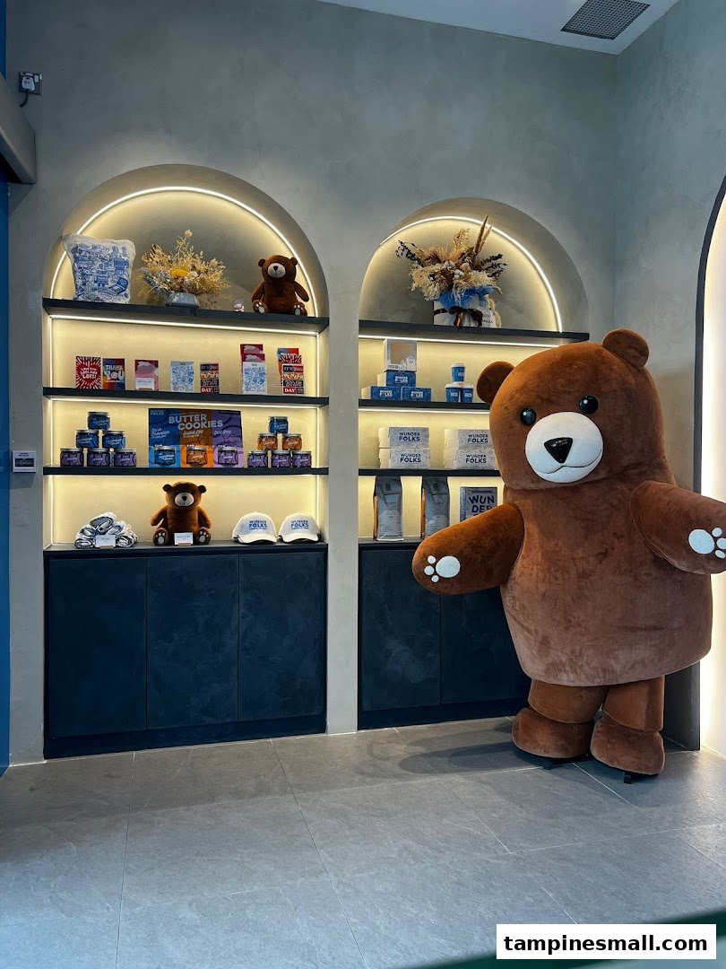 A large bear mascot stands beside shelves displaying merchandise and gifts inside Wunderfolks Pastry and Coffee.