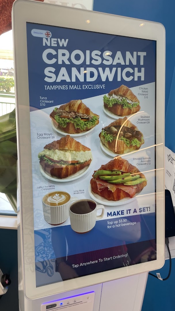 A digital menu display showcasing various croissant sandwiches and coffee options.