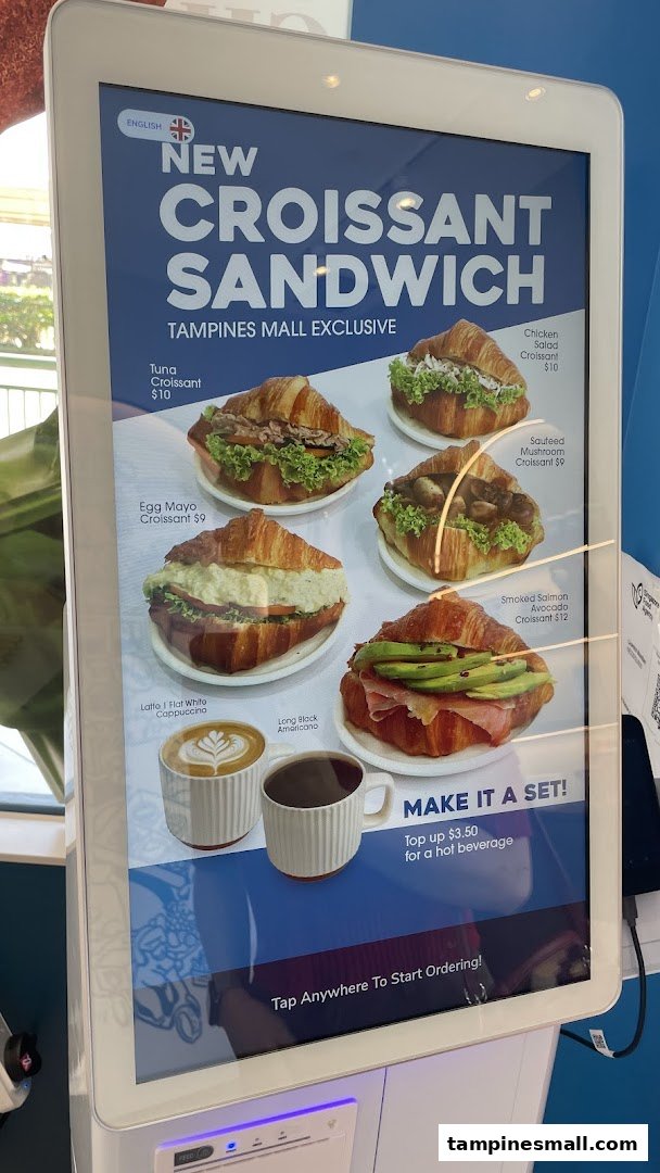 A digital menu display showcasing various croissant sandwiches and coffee options.