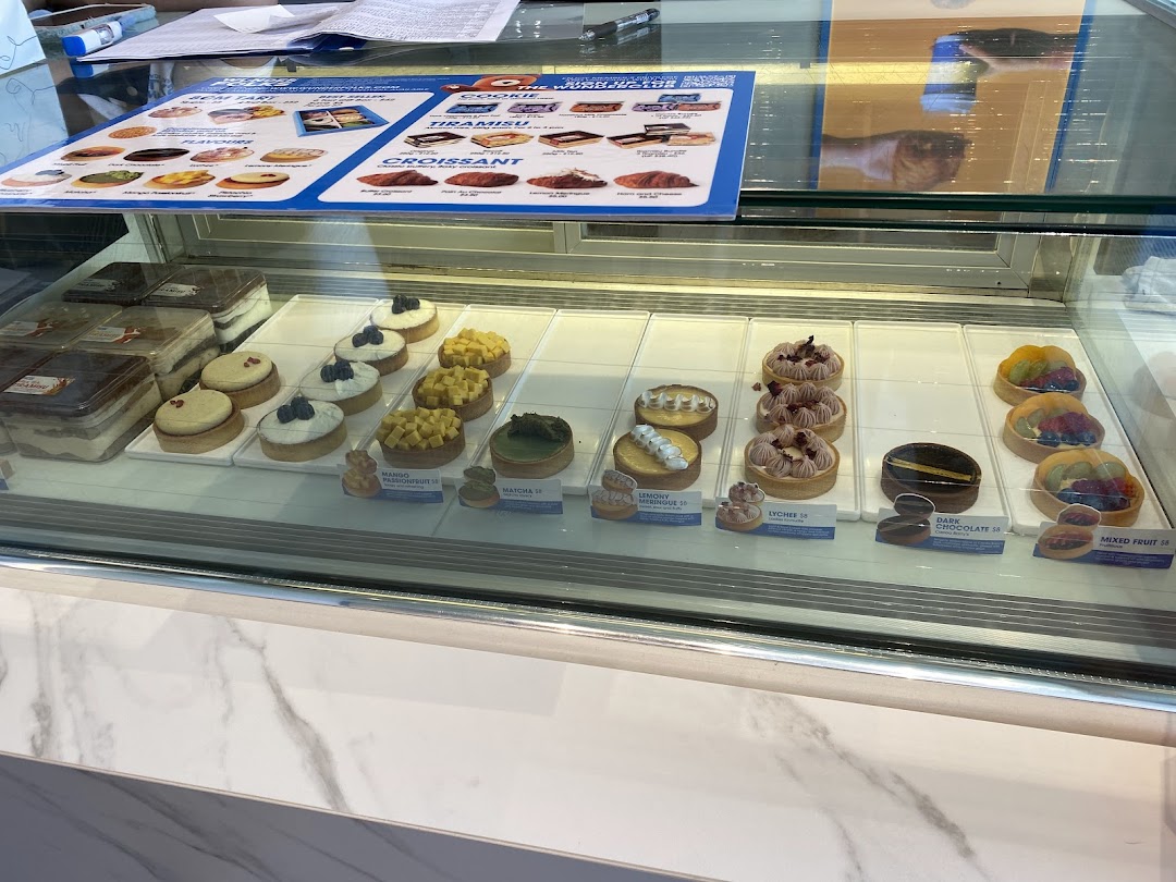 A vibrant display case showcasing a variety of freshly baked pastries, tarts, and tiramisu.