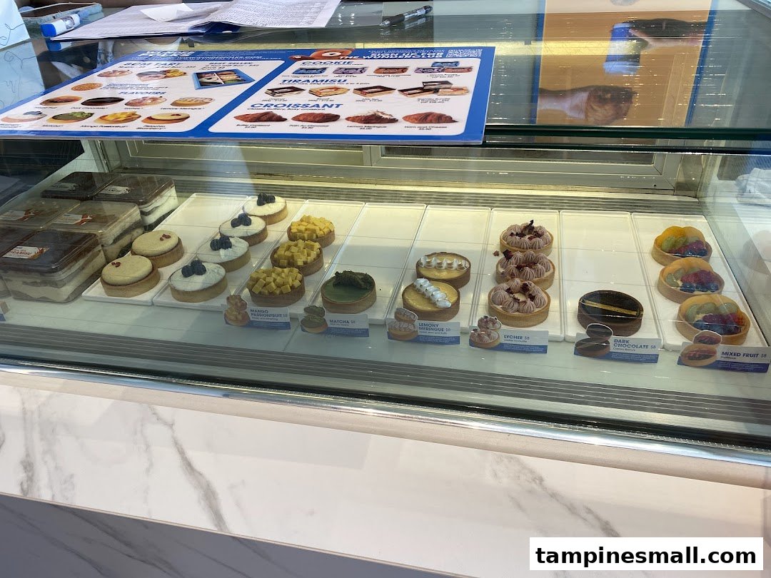A vibrant display case showcasing a variety of freshly baked pastries, tarts, and tiramisu.