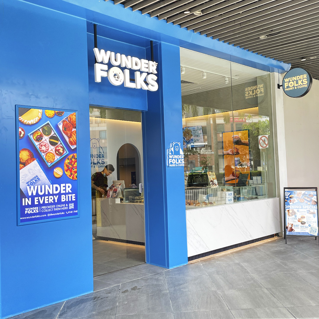Vibrant blue storefront of Wunderfolks Pastry & Coffee, showcasing its entrance and promotional poster.