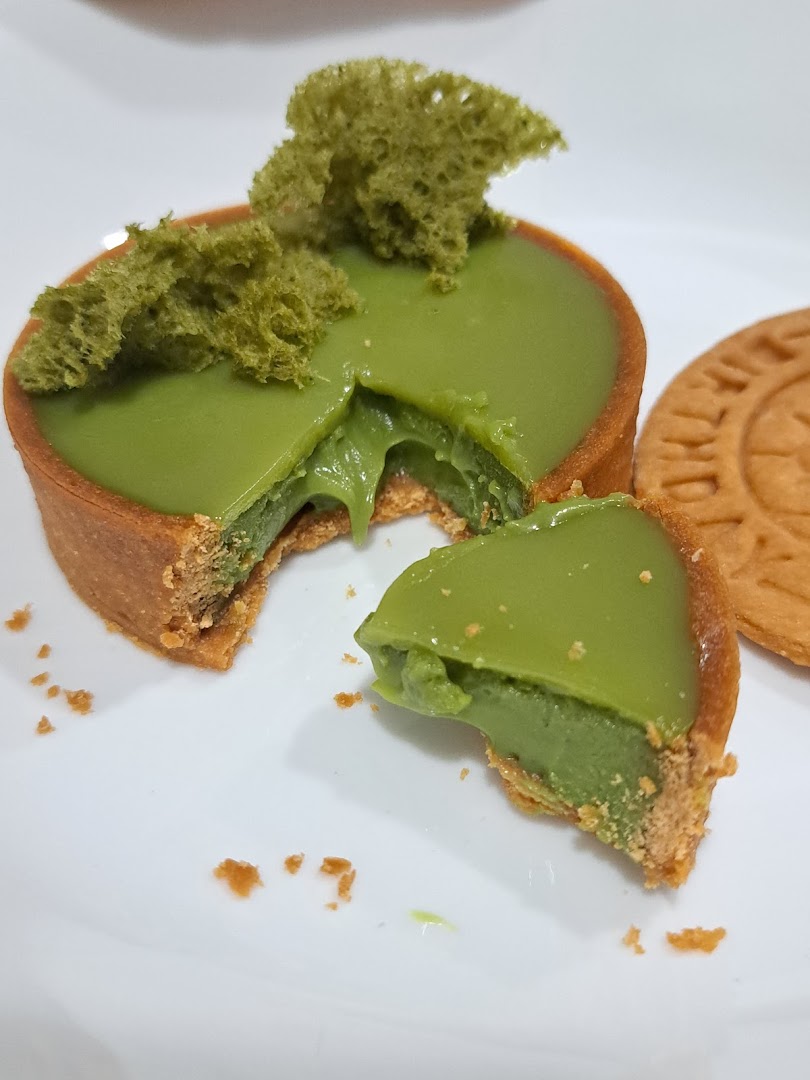 A close-up of a delicious green matcha tart with a piece removed, revealing its creamy filling.