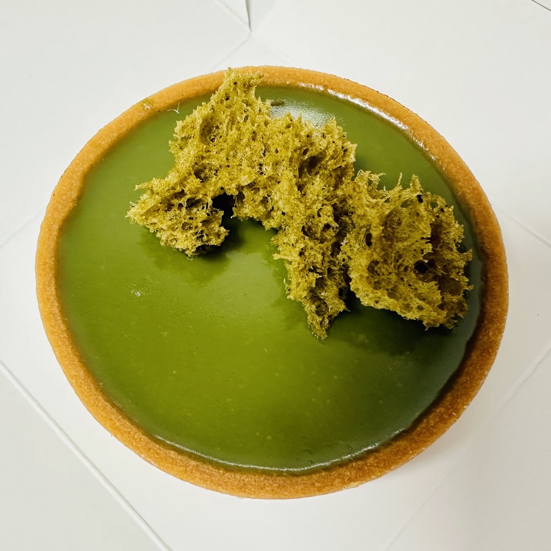 A vibrant green matcha tart with a crispy crust and unique textured topping.