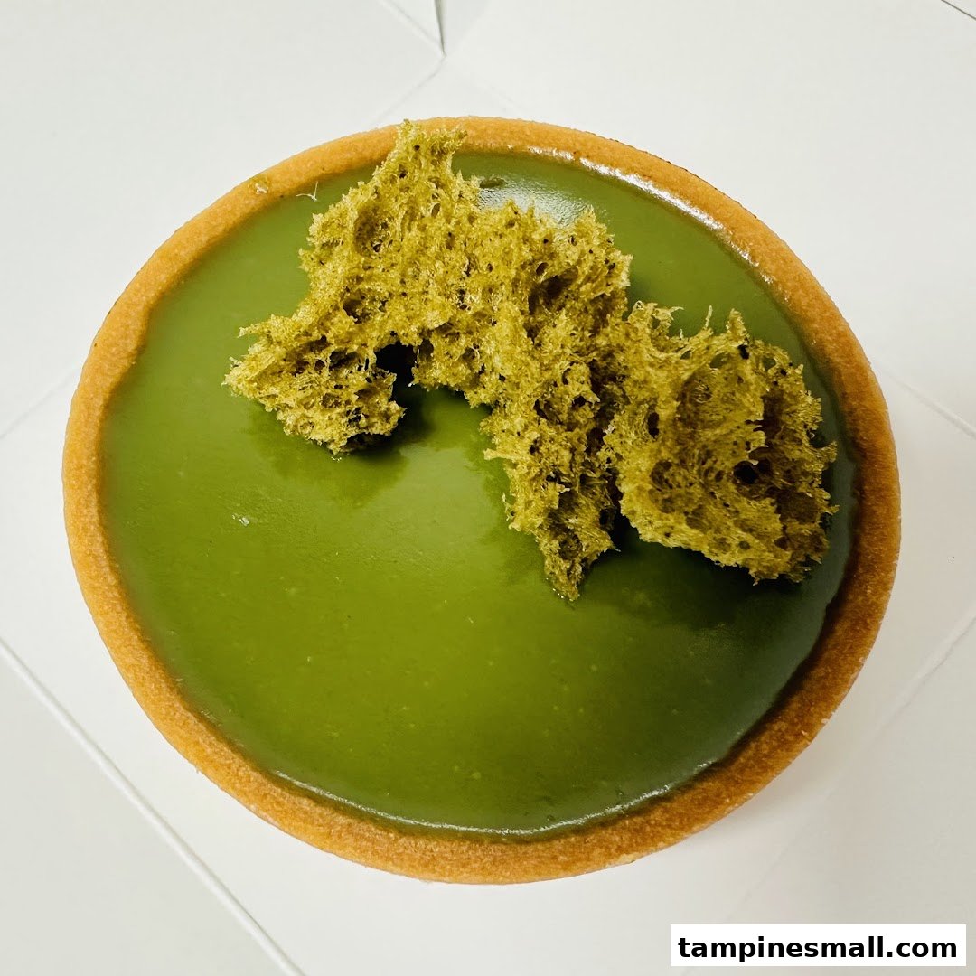 A vibrant green matcha tart with a crispy crust and unique textured topping.