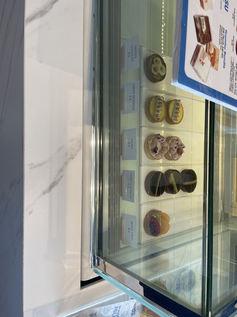 A vibrant display of artisanal tarts and pastries in a glass showcase.
