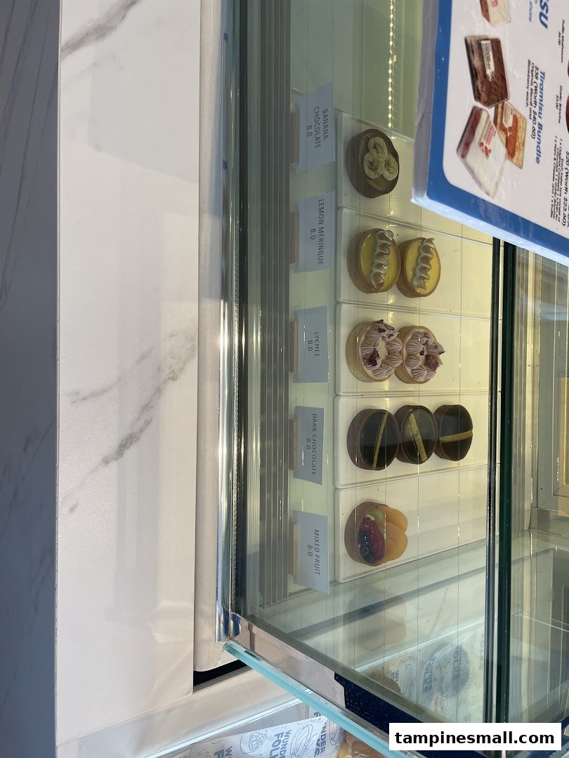 A vibrant display of artisanal tarts and pastries in a glass showcase.