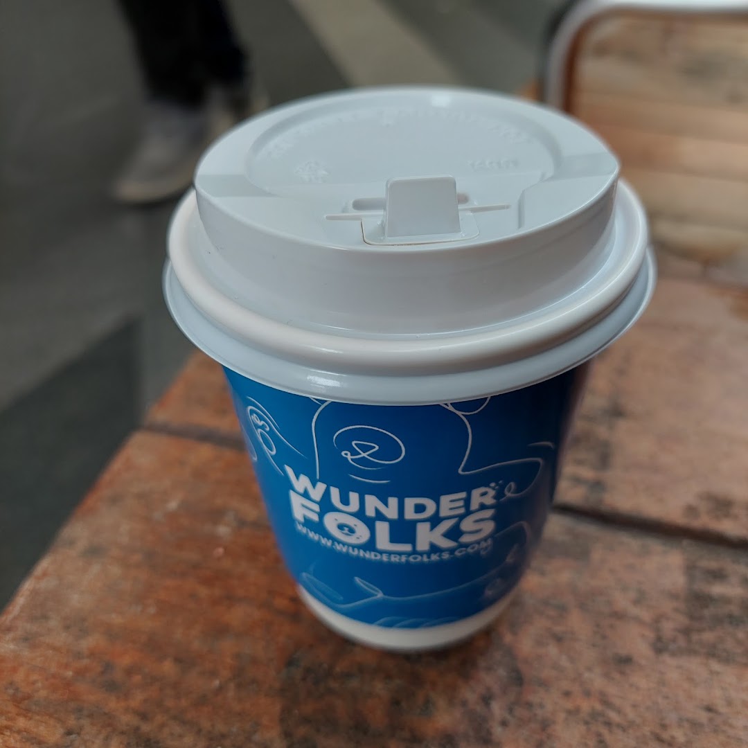 A blue and white coffee cup from Wunderfolks Pastry and Coffee sits on a wooden surface.