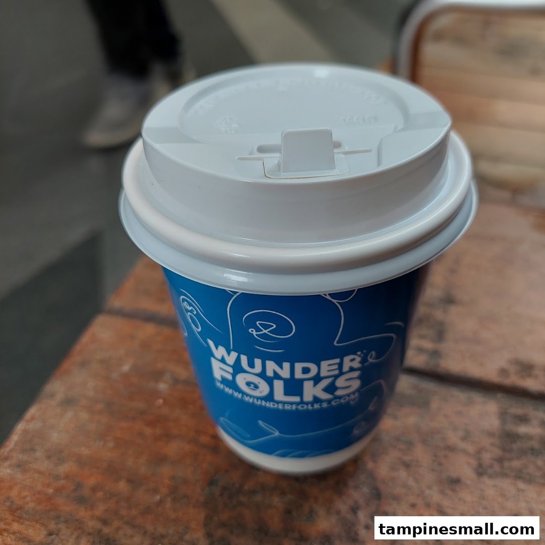 A blue and white coffee cup from Wunderfolks Pastry and Coffee sits on a wooden surface.