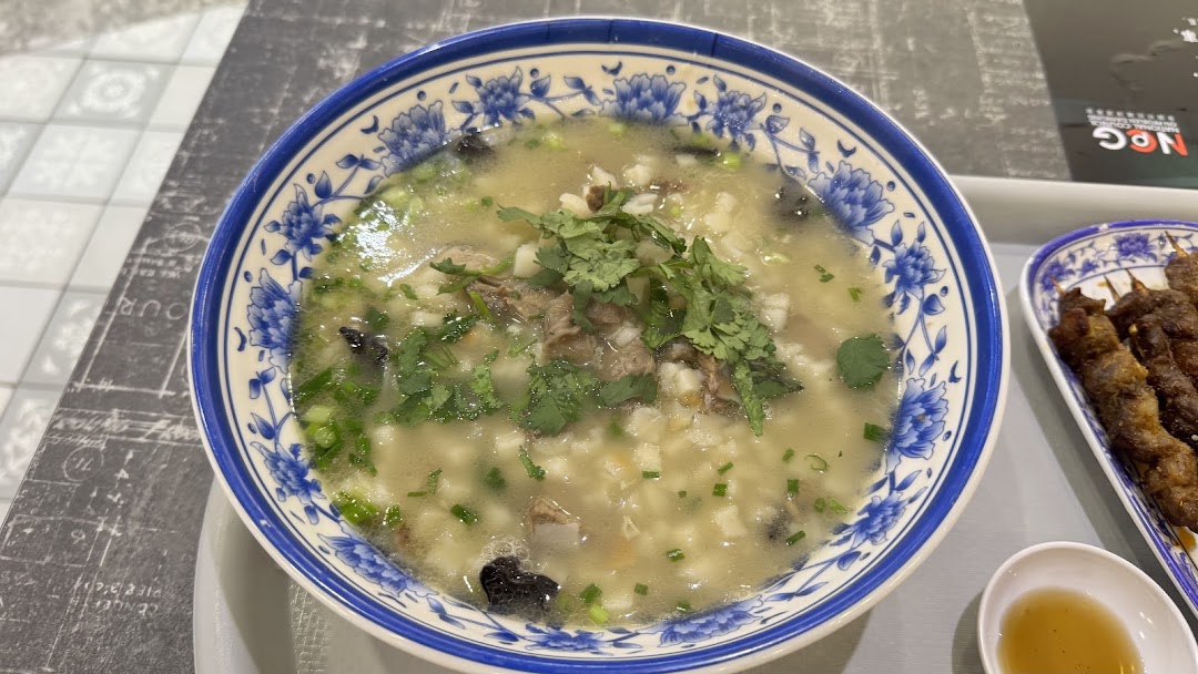 A hearty bowl of traditional Xi'an soup with meat and herbs, alongside grilled skewers.