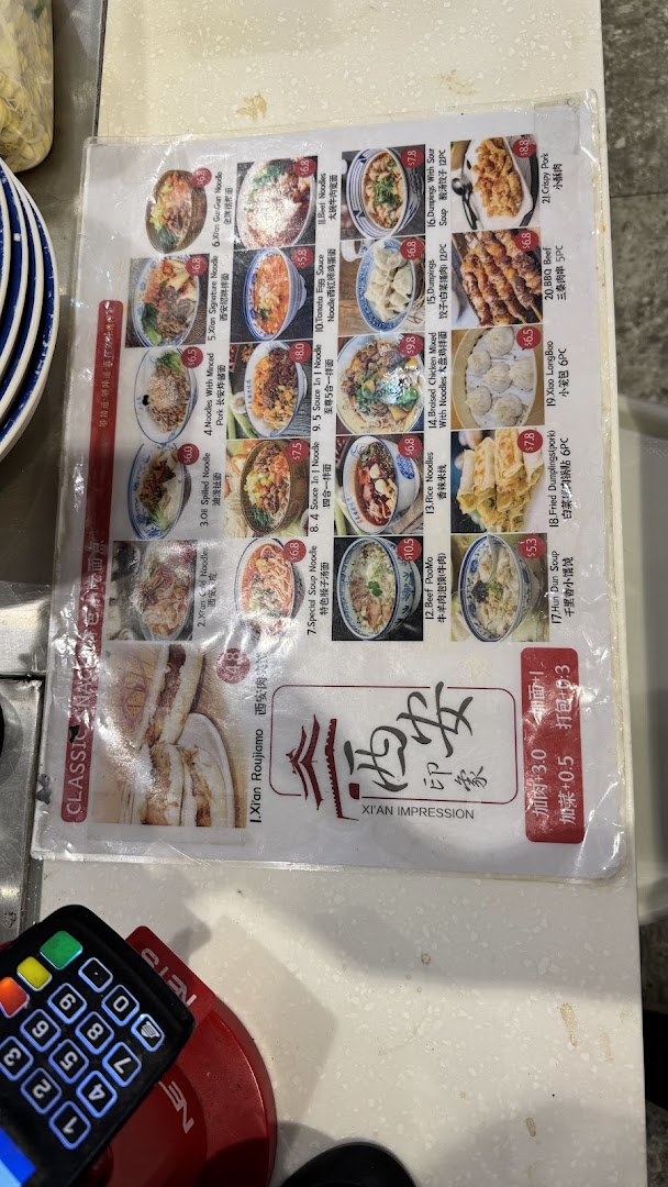 A laminated menu displaying various Xi'an cuisine dishes with prices and images.