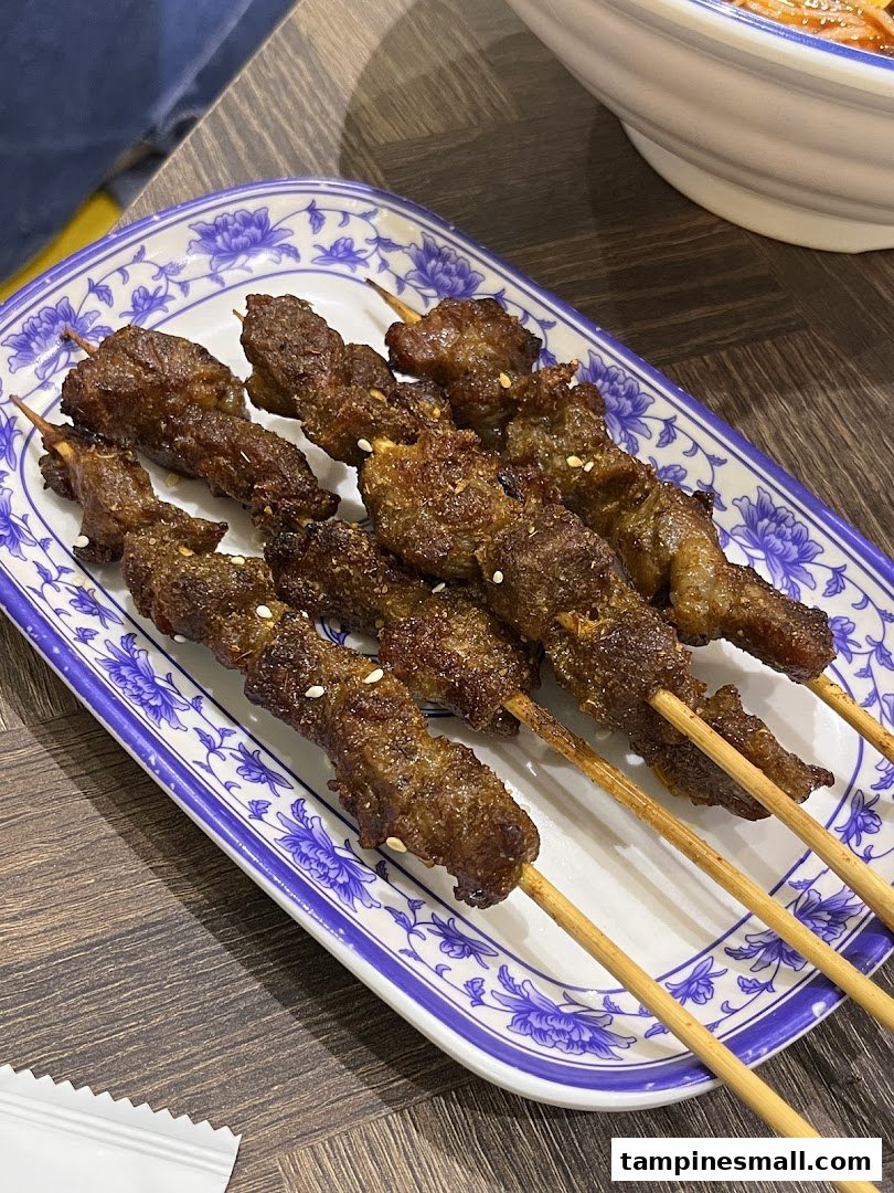 Close-up of several grilled meat skewers on a decorative white and blue plate.