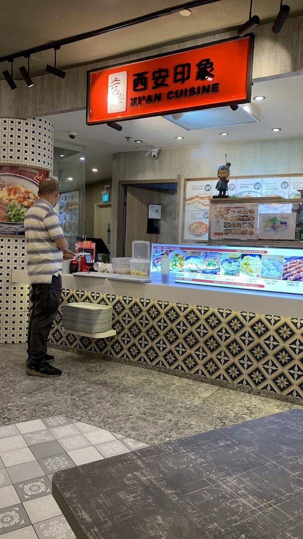 A customer stands at the counter of Xi'an Impression, a Chinese cuisine stall with food displays.