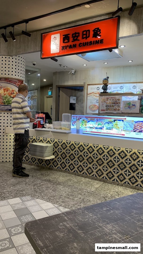 A customer stands at the counter of Xi'an Impression, a Chinese cuisine stall with food displays.
