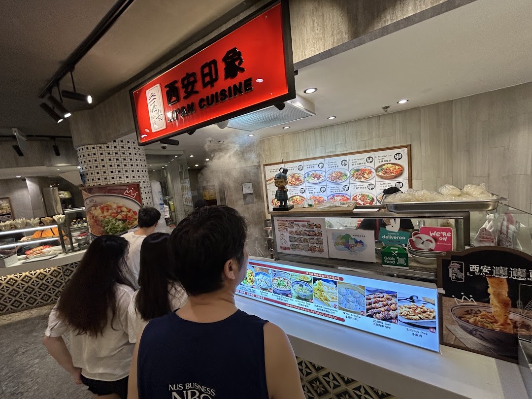Customers queueing at the counter of Xian Cuisine, a food stall with a prominent red sign and food displays.
