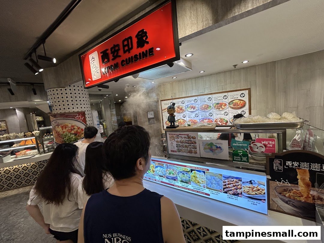 Customers queueing at the counter of Xian Cuisine, a food stall with a prominent red sign and food displays.