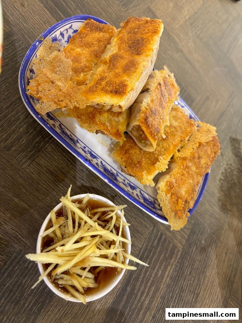 Crispy pan-fried dumplings served with a ginger and vinegar dipping sauce on a decorative plate.
