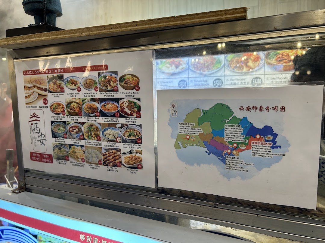 A display counter showcasing Xian Cuisine's menu with food photos, prices, and a map of their Singapore branches.