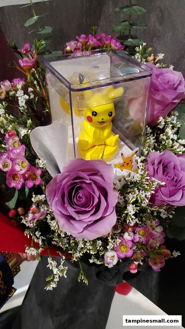A vibrant floral bouquet featuring purple roses and a Pikachu figurine in a clear box.