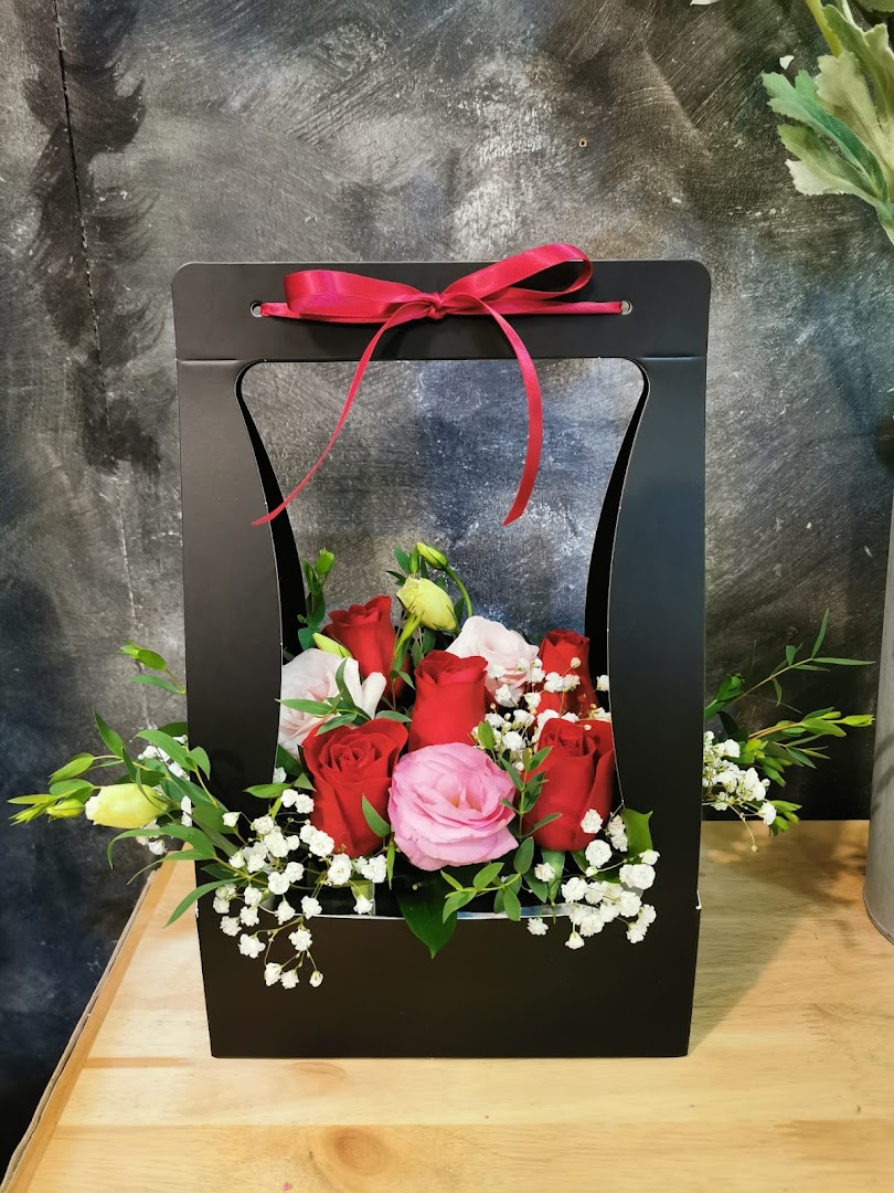 A vibrant bouquet of red and pink roses in a stylish black gift box with a red ribbon.