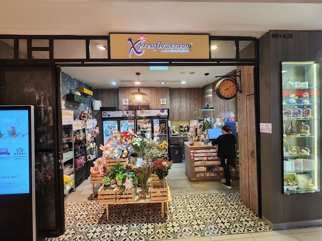 The Xpressflower shop entrance, showcasing fresh flowers, potted plants, and various gifts, with a staff member inside.