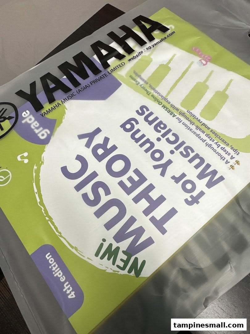 A Yamaha Music Theory book, 4th edition, for young musicians, seen through a plastic bag.