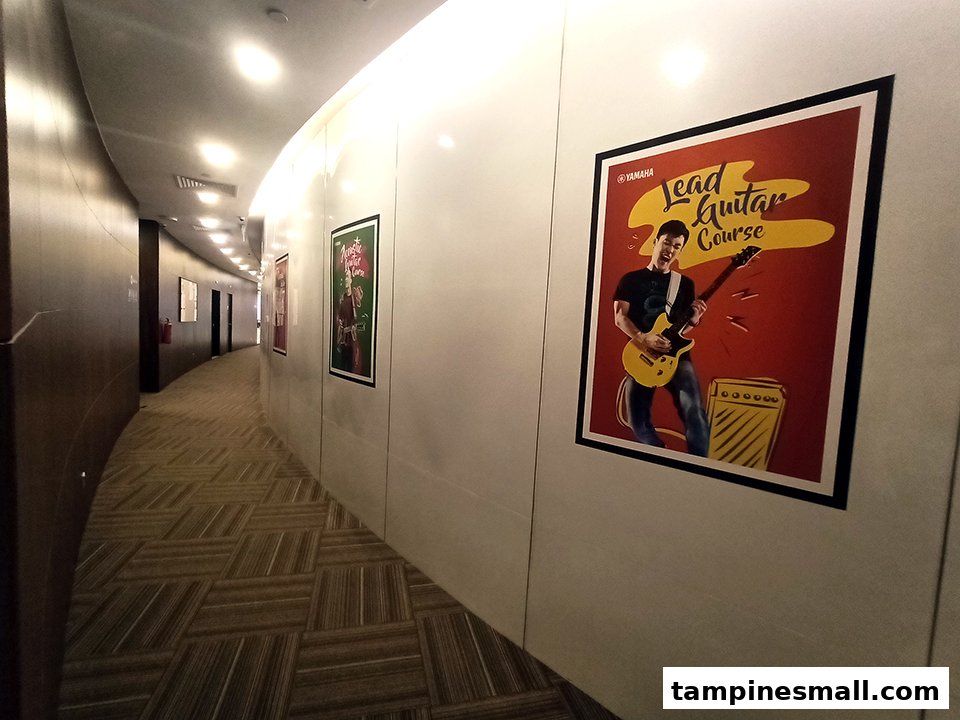 A brightly lit hallway adorned with posters advertising music courses, leading to the Yamaha Music School.
