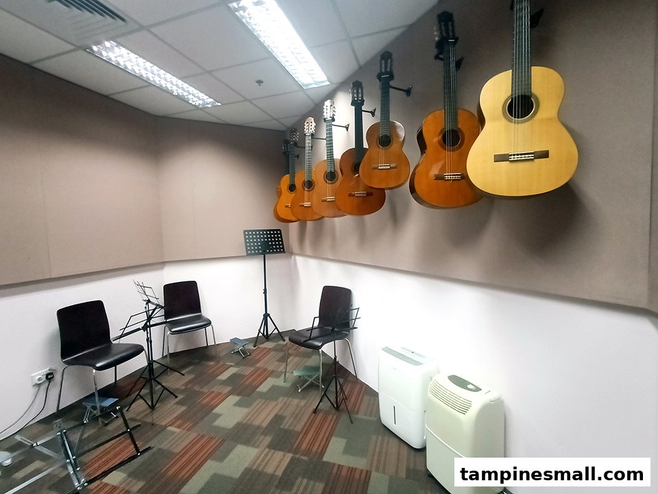 An interior view of a music classroom with guitars hanging on the wall, chairs, and music stands.
