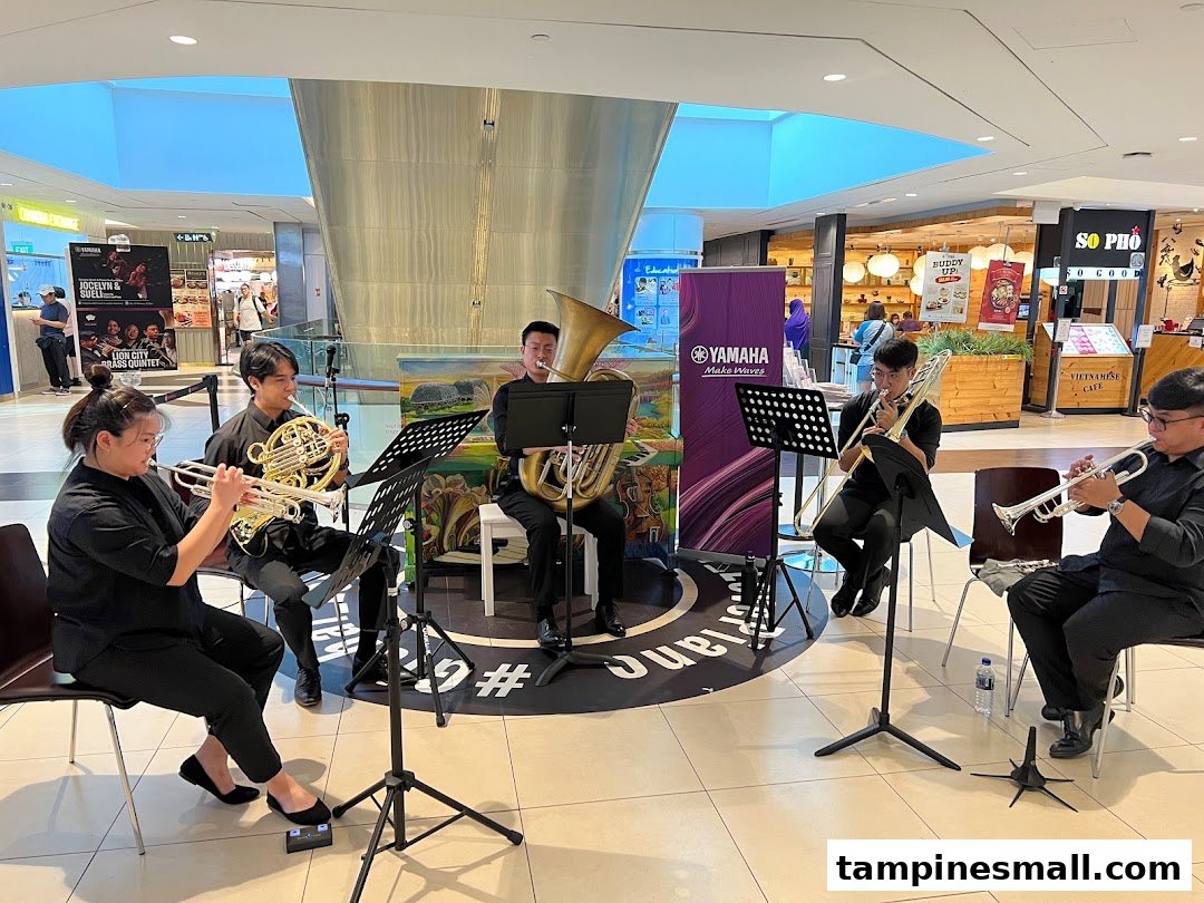 A brass quintet performs live in a shopping mall, featuring a Yamaha Music School banner.