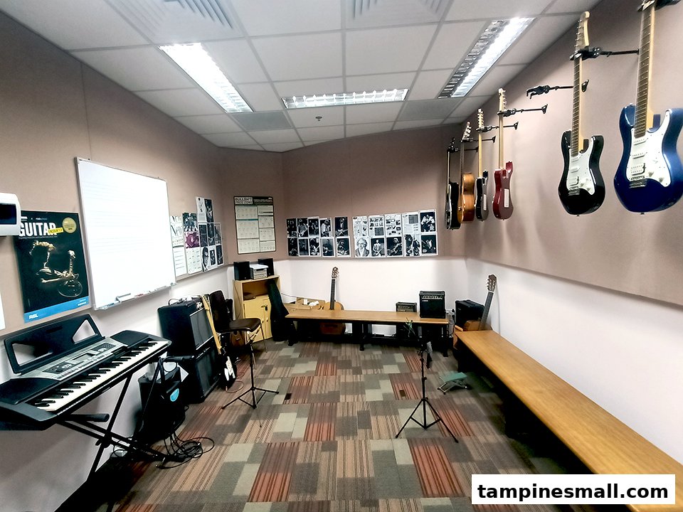 An interior view of a music classroom with guitars, a keyboard, and a whiteboard.