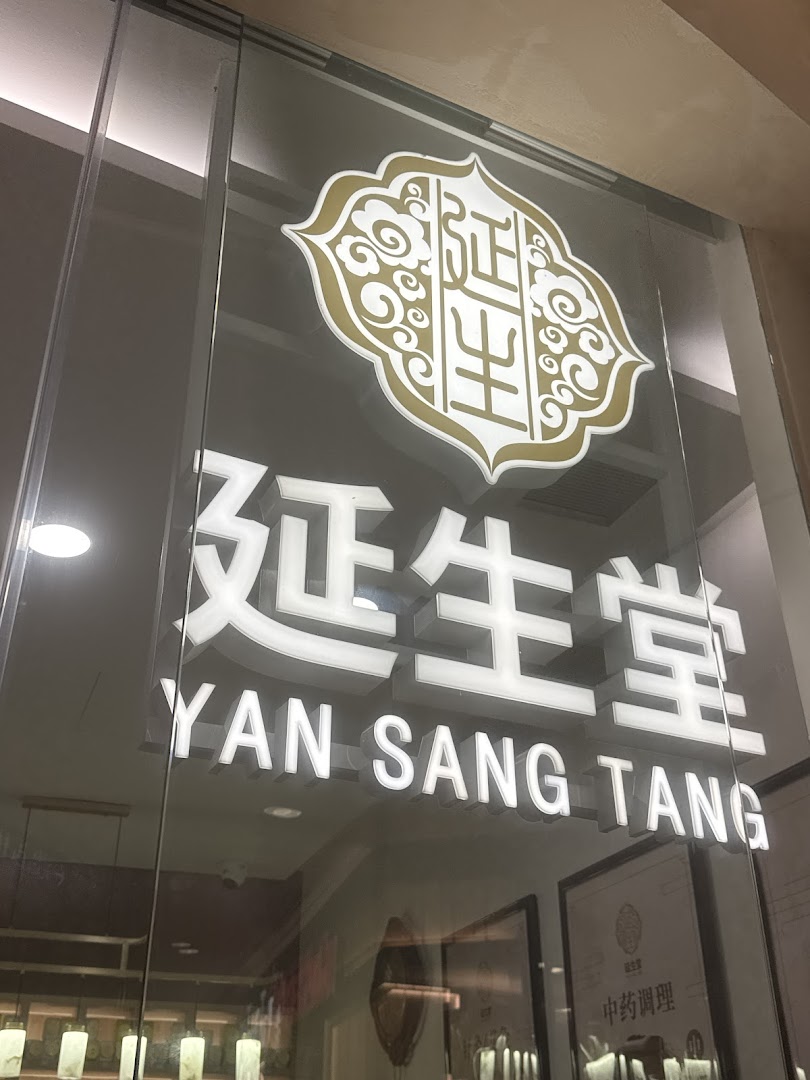 Close-up of the illuminated 'Yan Sang Tang' shop front signage on a glass door.
