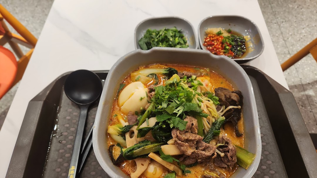 A vibrant bowl of Mala Tang with various ingredients and side condiments on a tray.