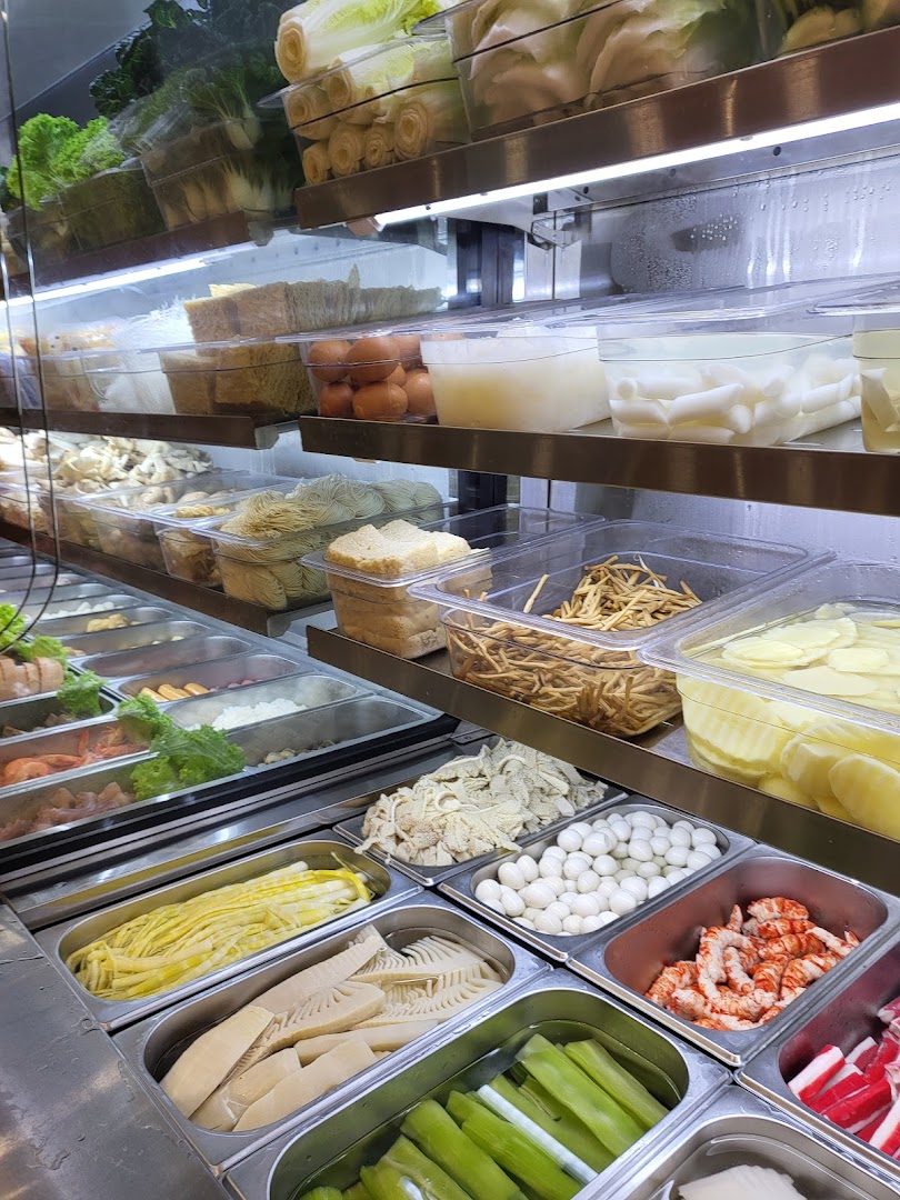A vibrant display of fresh ingredients, including vegetables, meats, and noodles, in a refrigerated case.