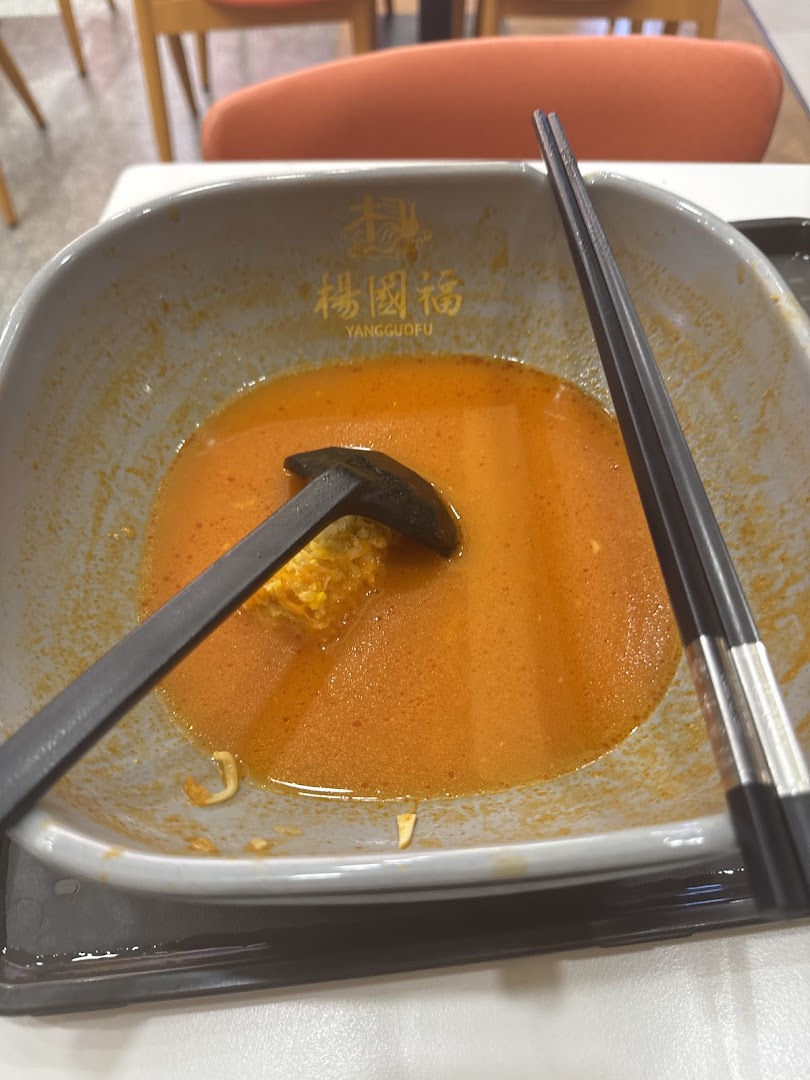 A close-up of a nearly finished bowl of spicy Mala Tang from Yang Guo Fu, with chopsticks and a ladle.