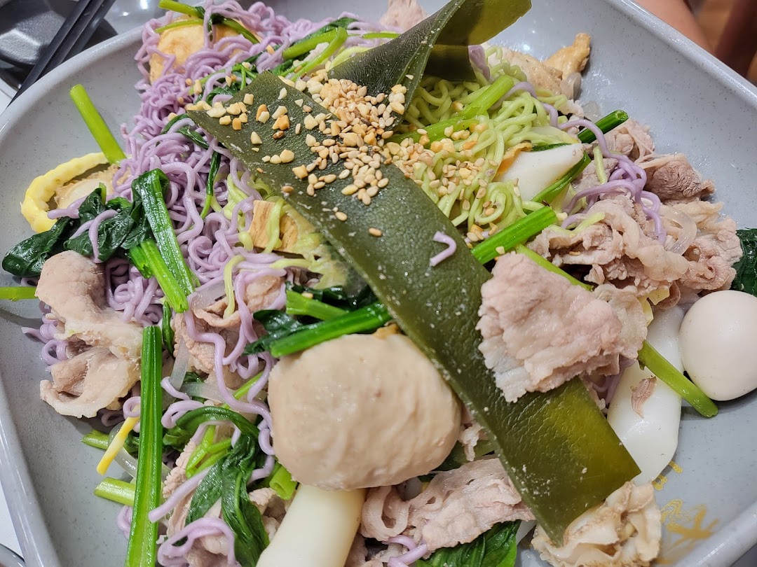 A vibrant bowl of mala tang featuring colorful noodles, meat, vegetables, and toppings.