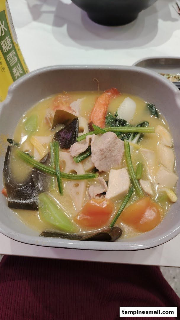 A vibrant bowl of Mala Tang soup filled with various fresh ingredients and meats.