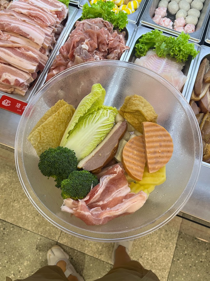 A clear bowl filled with various fresh ingredients for Mala Tang, selected from a self-serve counter.