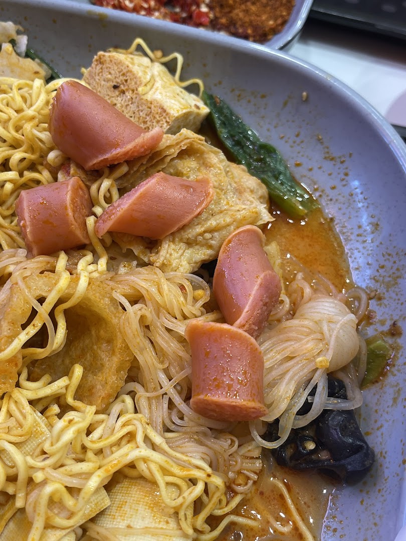 A close-up of a delicious bowl of Mala Tang with noodles, sausages, and vegetables.