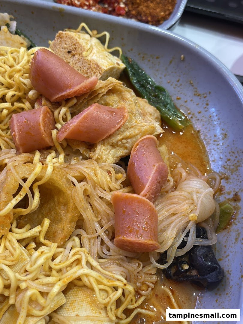 A close-up of a delicious bowl of Mala Tang with noodles, sausages, and vegetables.