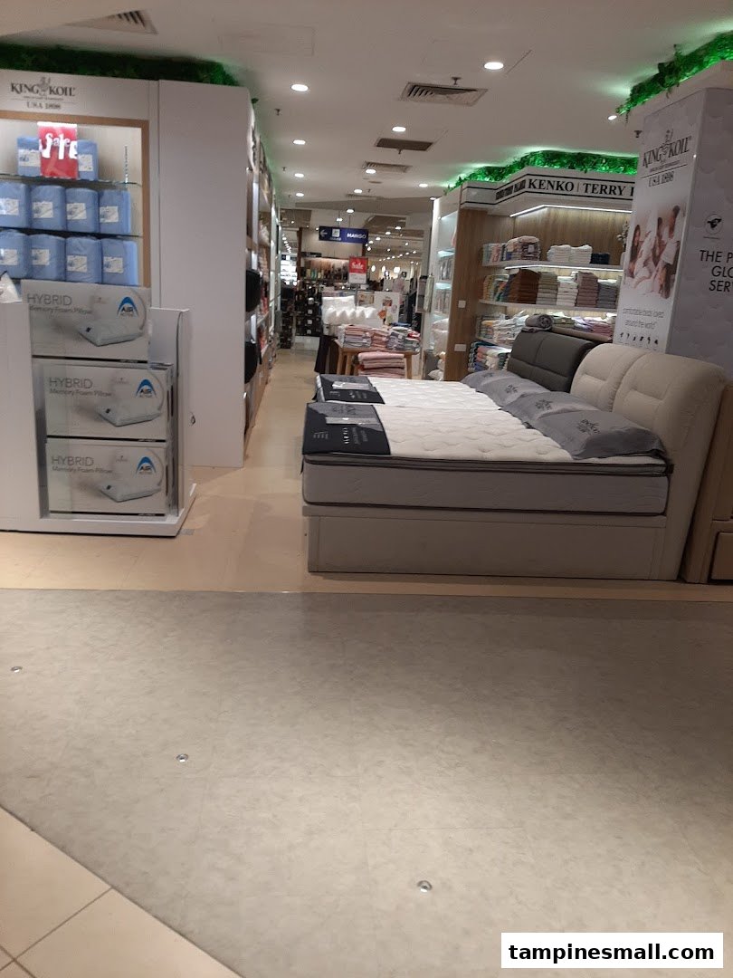 An interior view of a department store's bedding and mattress section, featuring various home comfort products.