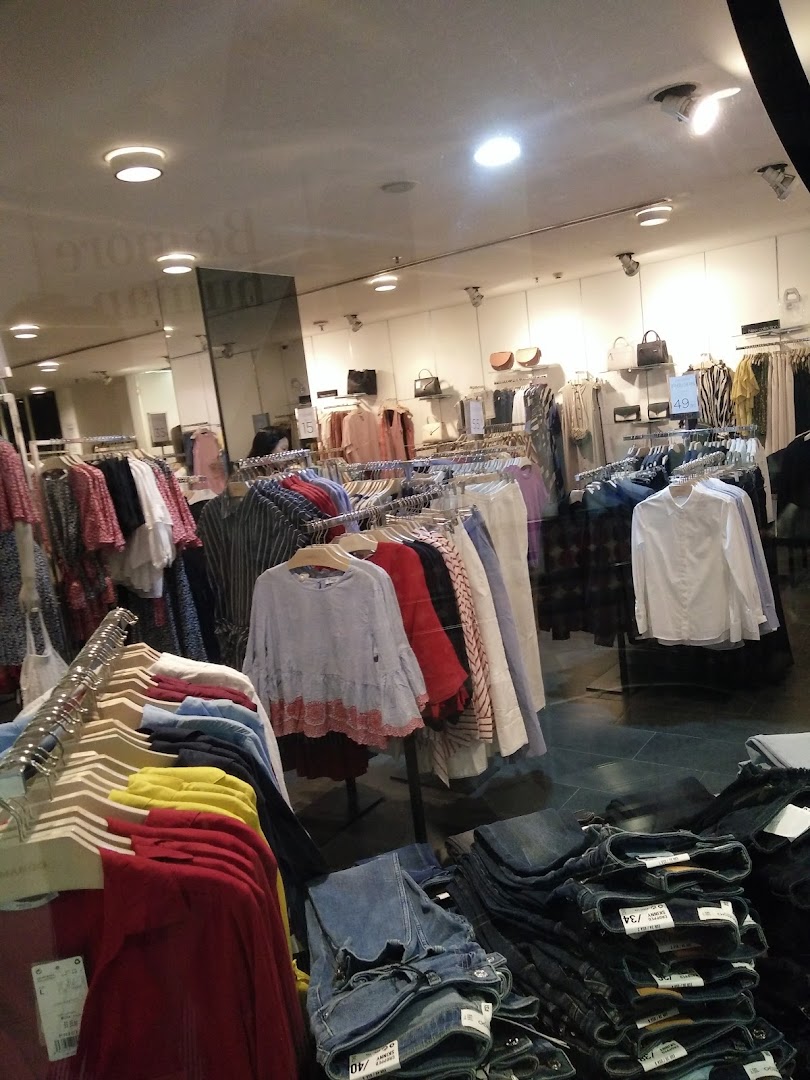 Interior view of a clothing store showcasing various apparel on racks and folded jeans.
