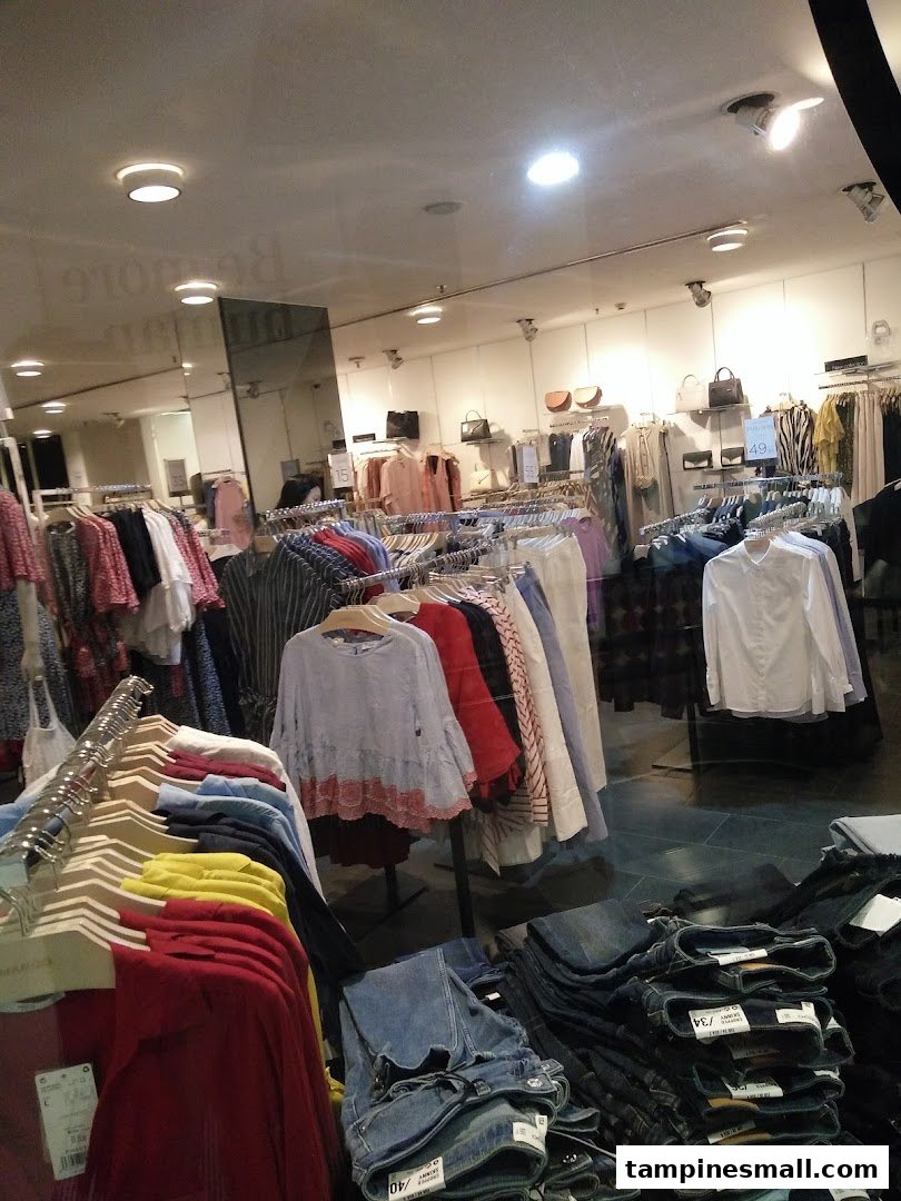 Interior view of a clothing store showcasing various apparel on racks and folded jeans.