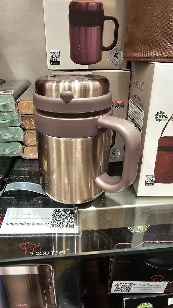 Close-up of 'a gourmet' brand thermal food jars and mugs displayed in a retail setting.