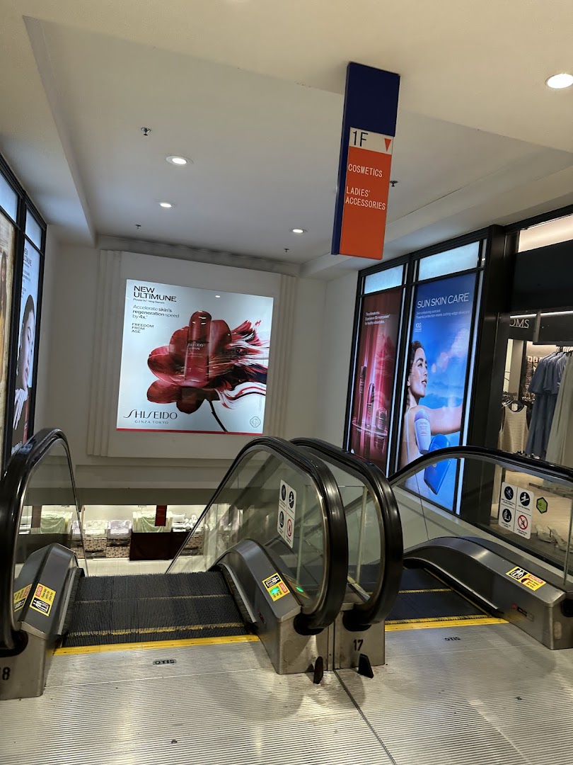 An escalator leading to the 1st floor, featuring beauty and fashion departments with prominent Shiseido ads.