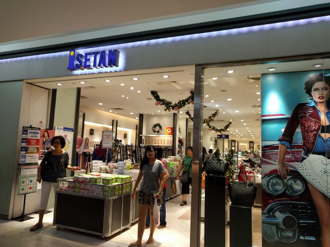 The brightly lit entrance of Isetan Tampines, featuring shoppers and festive decorations.