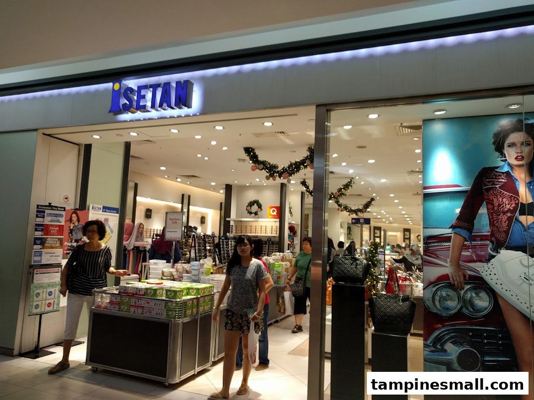 The brightly lit entrance of Isetan Tampines, featuring shoppers and festive decorations.