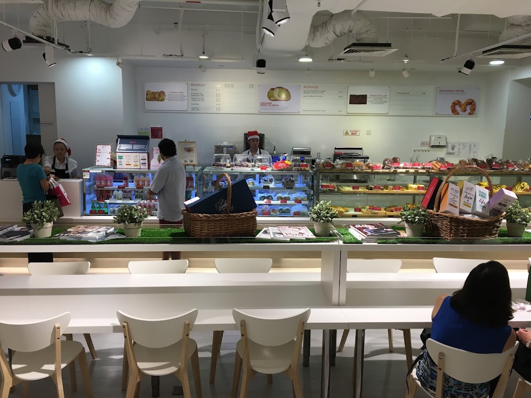 Bright interior of a modern bakery and cafe with display cases, counter, and seating.