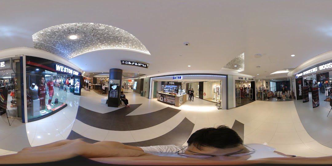 An interior view of a modern shopping mall showcasing various retail outlets including Isetan, Weston Corp, and Mango.