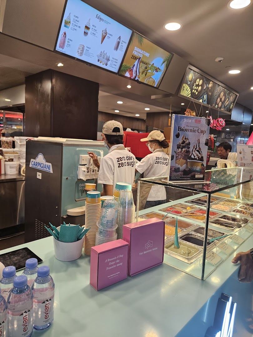 Interior view of Yolé frozen yogurt shop with staff, counter, and digital menu boards.