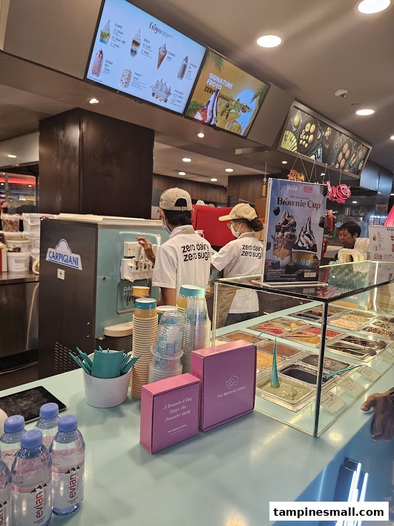 Interior view of Yolé frozen yogurt shop with staff, counter, and digital menu boards.